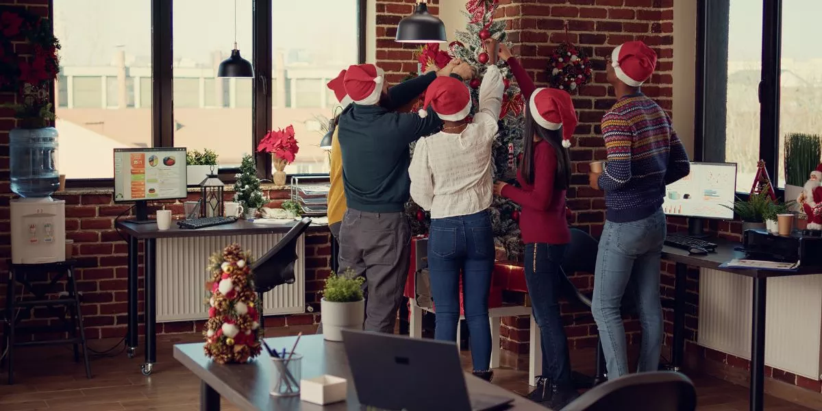 Equipo de trabajadores decorando juntos el árbol de navidad de la oficina 