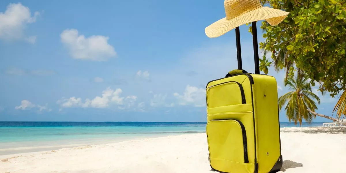 Valija sobre la arena frente al mar, representando el descanso y las vacaciones laborales. 