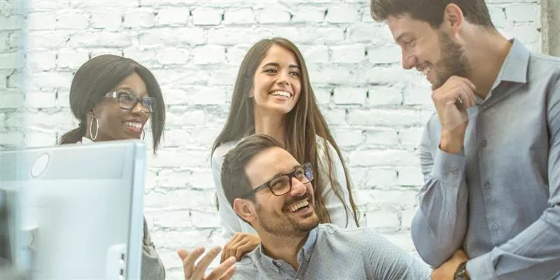 Equipo de colaboradores conversando y trabajando juntos en una oficina, representando el compromiso y la retención del personal en las empresas.