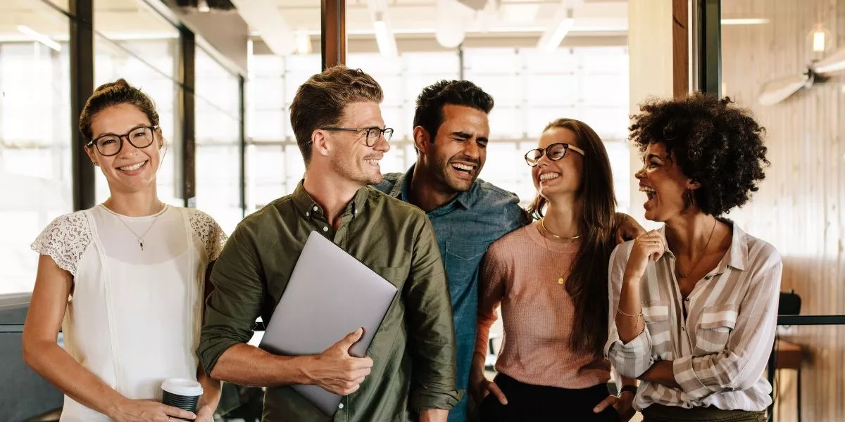 Equipo de trabajo sonriendo en la oficina, reflejando motivación y buen clima laboral en un entorno corporativo en Uruguay. 