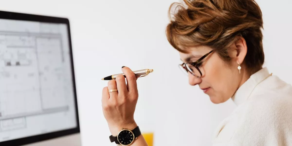 Mujer en entorno corporativo evaluando alternativas de beneficios corporativos frente a una computadora, con lapicera en la mano, analizando opciones para la gestión de proveedores.