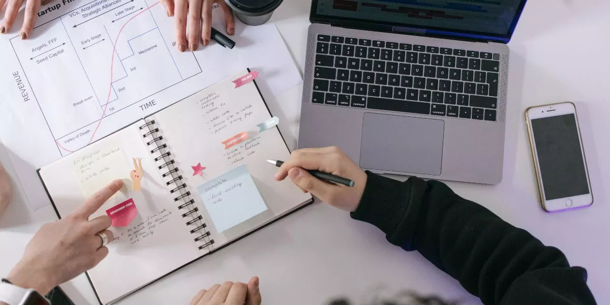 Equipo organizándose en el trabajo y gestionando tareas con agenda y computadora