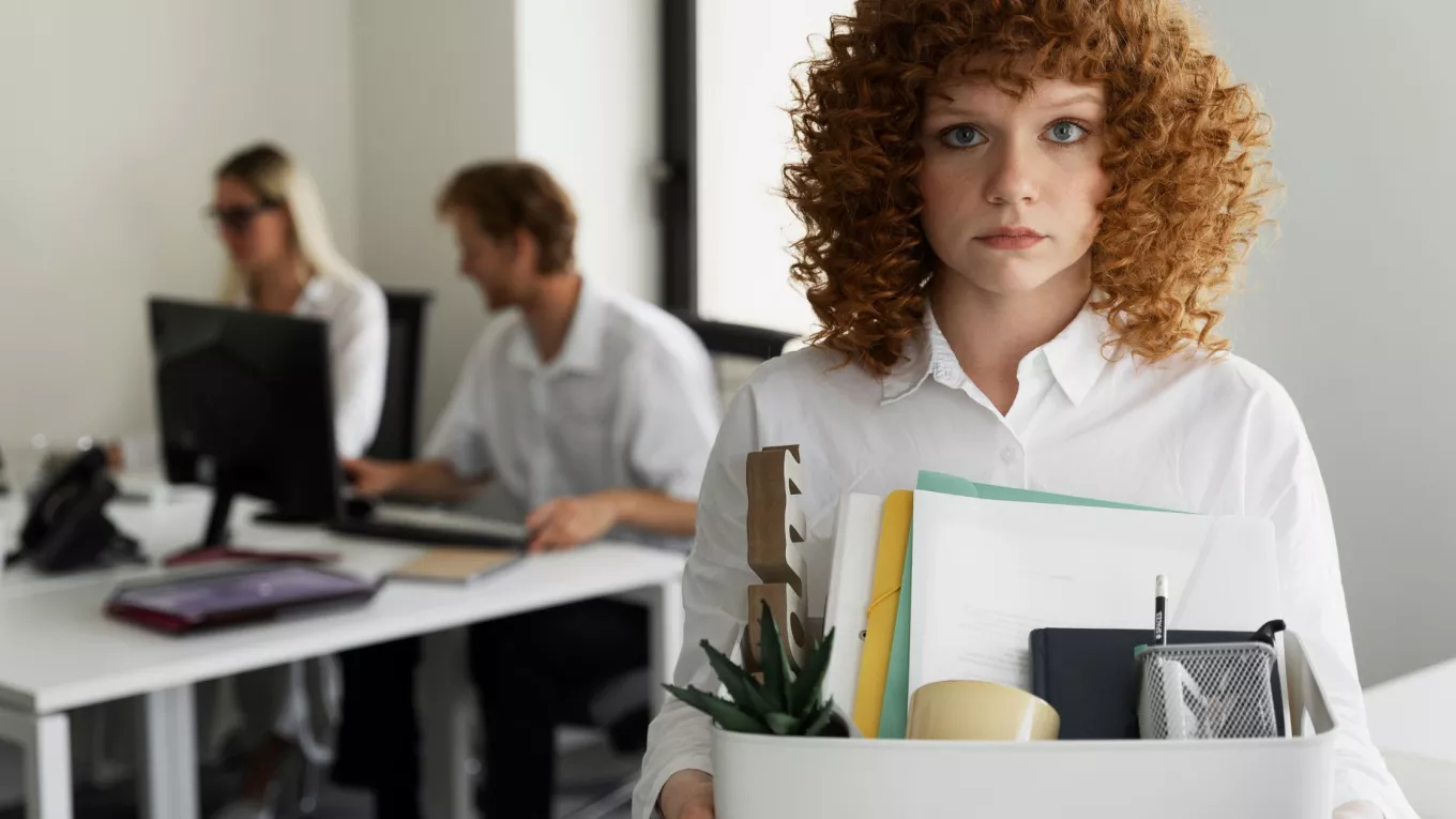 Colaboradora dejando la oficina con sus pertenencias tras una renuncia laboral vinculada a la rotación de personal en empresas. 