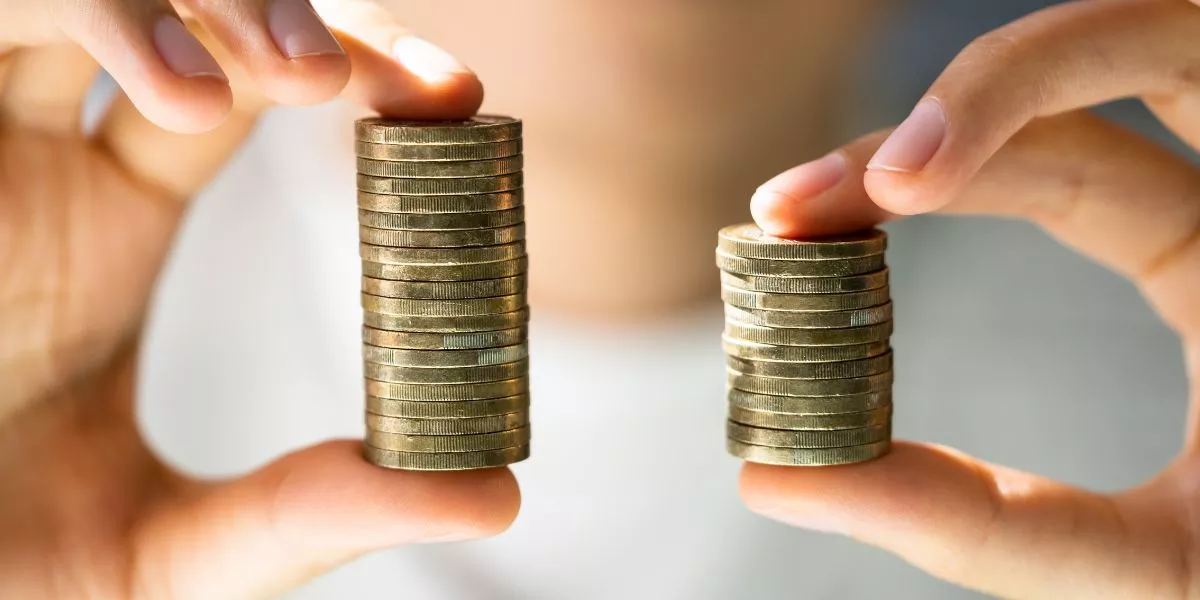 Manos sostienen dos pilas de monedas de diferente altura para representar un aumento de sueldo. 