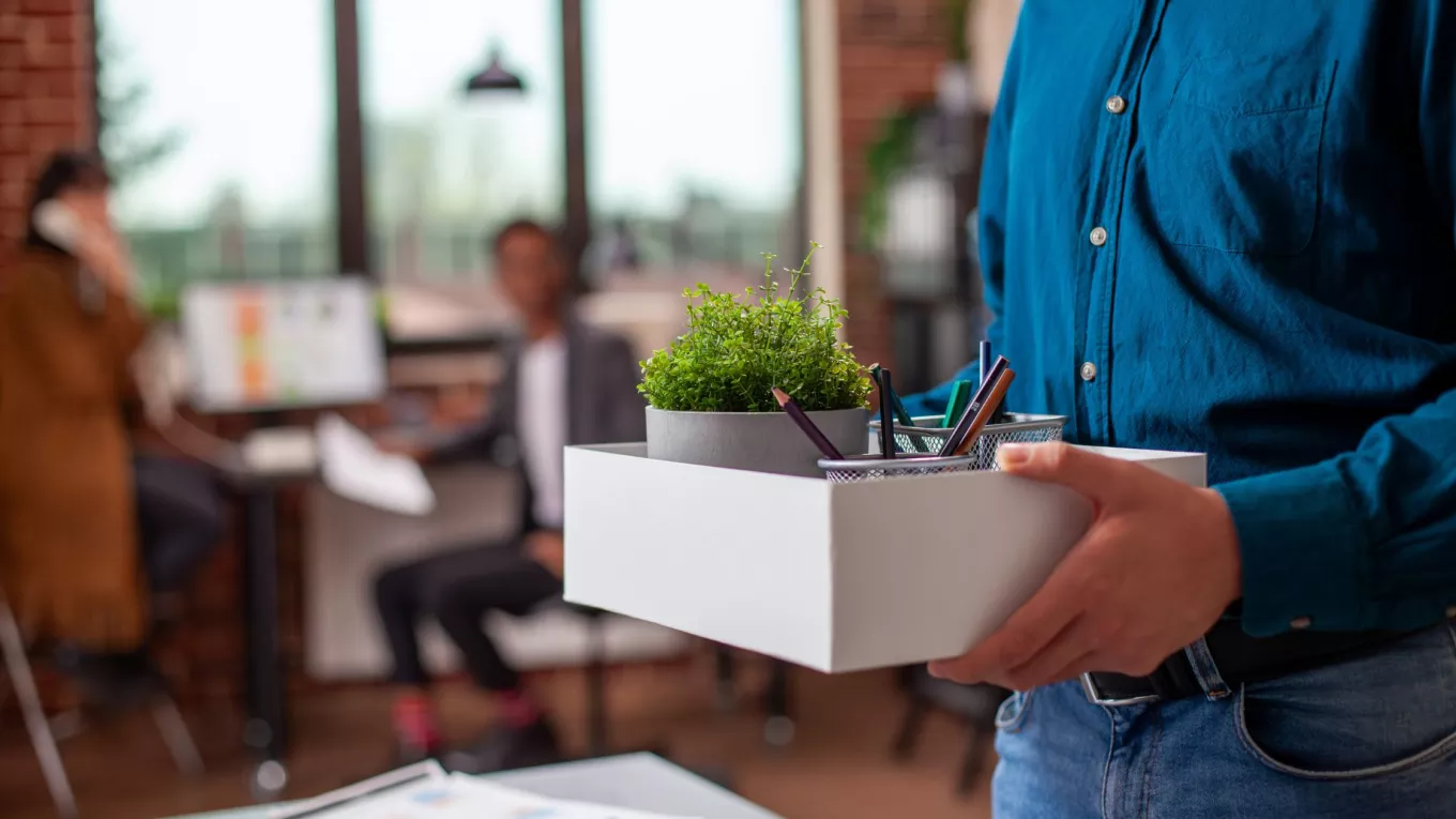 Colaborador sosteniendo una caja con sus pertenencias durante un proceso de offboarding en la oficina.