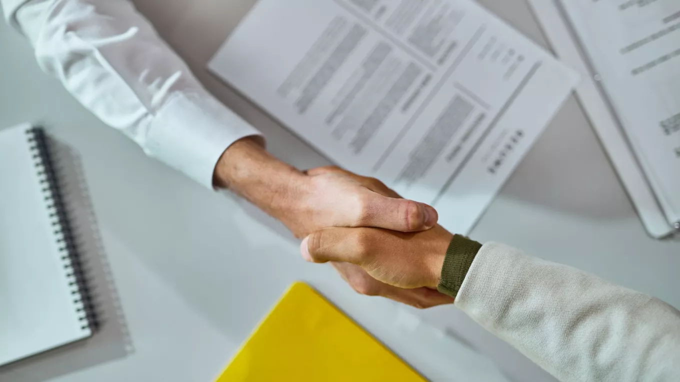 Persona estrechando la mano de un colaborador durante un proceso de offboarding en una oficina.
