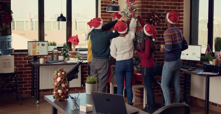 Equipo de trabajadores decorando juntos el árbol de navidad de la oficina