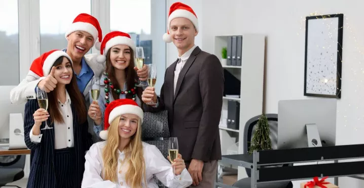 Equipo de oficina celebrando la Navidad con gorros rojos y copas de brindis