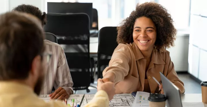 Persona joven sonriendo y estrechando la mano en una entrevista laboral, representando el crecimiento del mercado laboral uruguayo.