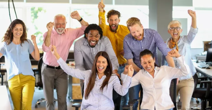 Equipo de trabajo celebrando juntos en la oficina durante una actividad de team building.