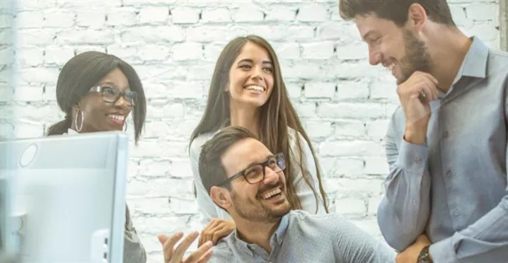 Equipo de colaboradores conversando y trabajando juntos en una oficina, representando el compromiso y la retención del personal en las empresas.