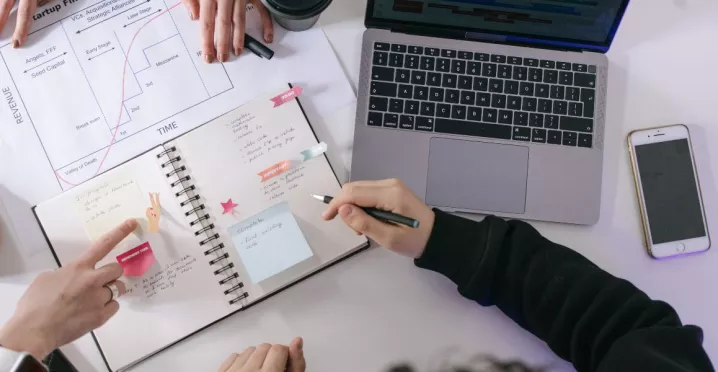 Equipo organizándose en el trabajo y gestionando tareas con agenda y computadora