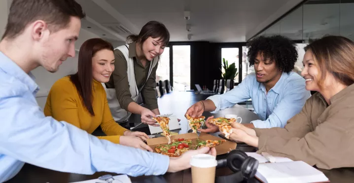 Equipo de trabajo compartiendo una comida en oficina, relacionado con gestión de gastos y reducción de costos de alimentación en una empresa