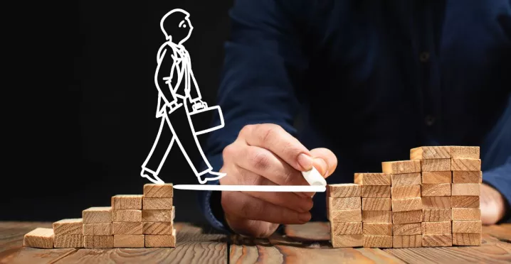 Plan de desarrollo profesional representado con bloques y figura avanzando en carrera laboral