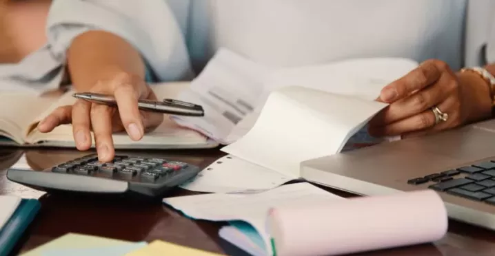 Persona revisando cuentas y documentos para consultar la devolución del IRPF en Uruguay desde una computadora portátil.
