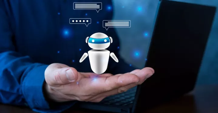 Persona sosteniendo un agente de inteligencia artificial virtual frente a una computadora, representando el uso de IA en Recursos Humanos para automatizar procesos.