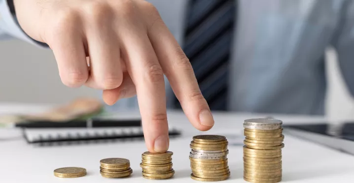 Mano acomodando pilas de monedas que representan el crecimiento de los salarios en Uruguay y la evolución del poder adquisitivo de los trabajadores.