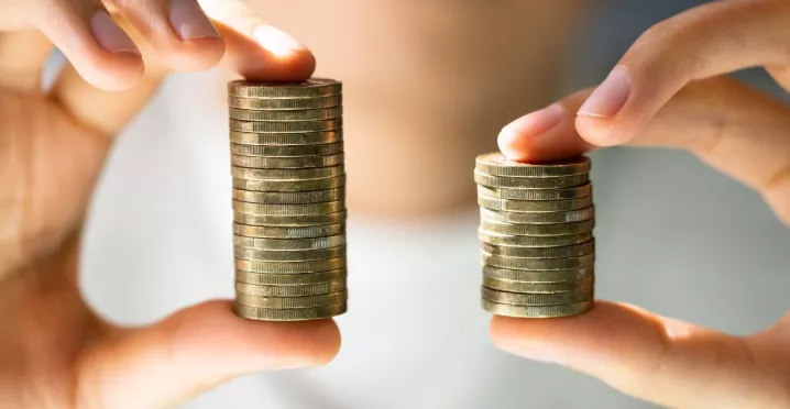 Manos sostienen dos pilas de monedas de diferente altura para representar un aumento de sueldo.