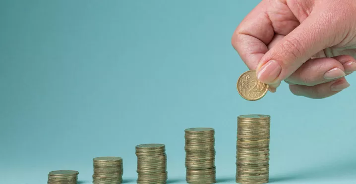 Mano colocando una moneda sobre pilas crecientes que representan el ajuste salarial 2026 en Uruguay.