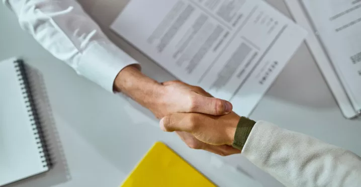Persona estrechando la mano de un colaborador durante un proceso de offboarding en una oficina.