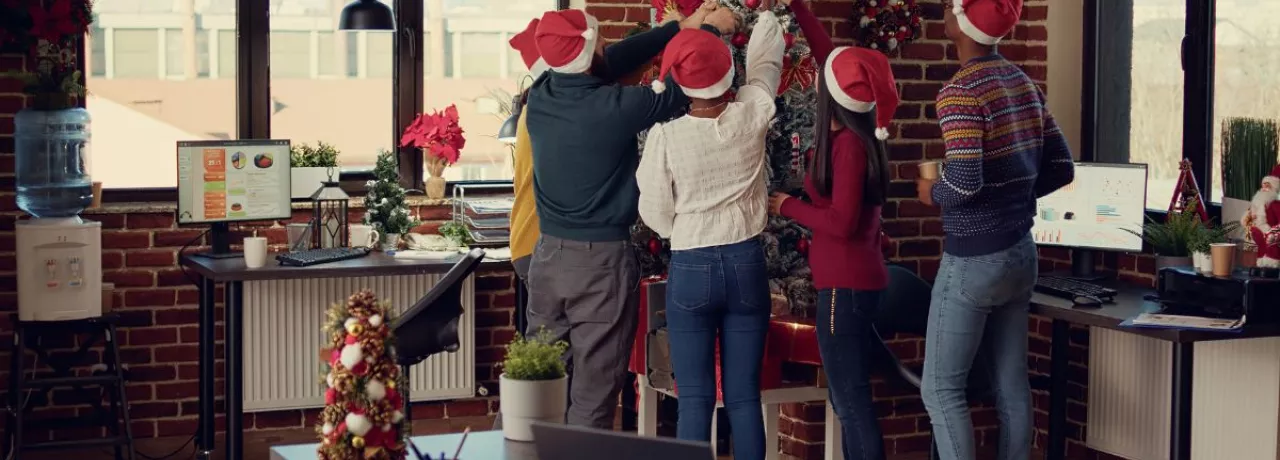 Equipo de trabajadores decorando juntos el árbol de navidad de la oficina