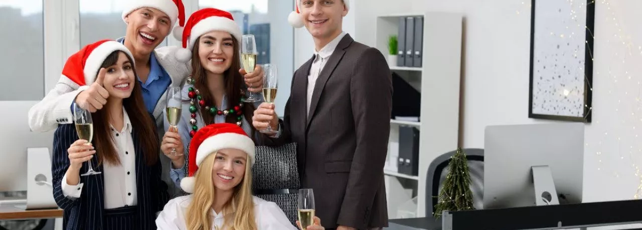 Equipo de oficina celebrando la Navidad con gorros rojos y copas de brindis