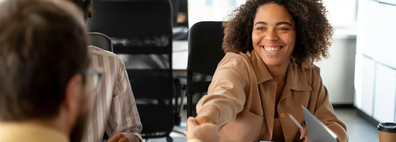 Persona joven sonriendo y estrechando la mano en una entrevista laboral, representando el crecimiento del mercado laboral uruguayo.