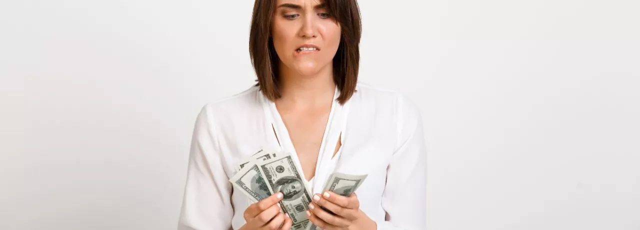 Mujer observando billetes de dinero con gesto de preocupación, reflejando la brecha entre salario real y salario percibido.