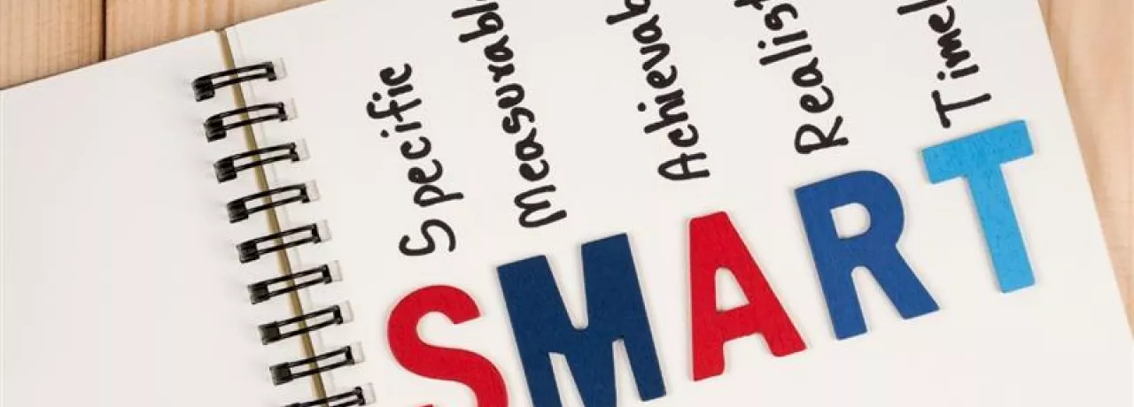Cuaderno con la palabra SMART y sus componentes específicos, medibles, alcanzables, relevantes y con plazo, representando la metodología para definir objetivos SMART.