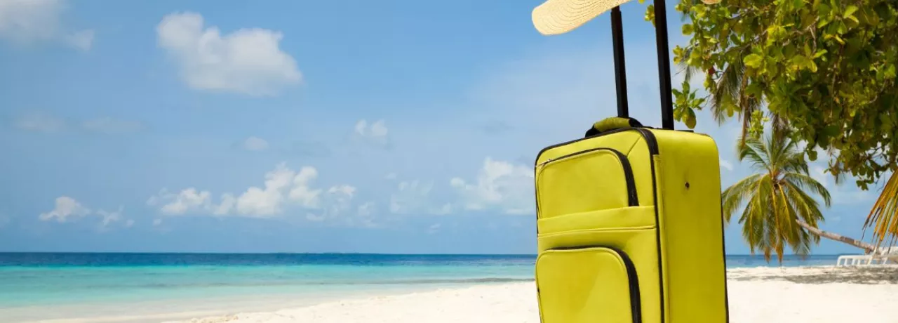 Valija sobre la arena frente al mar, representando el descanso y las vacaciones laborales.