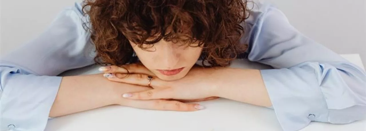 Colaboradora preocupada por su situación financiera, con un billete sobre el escritorio