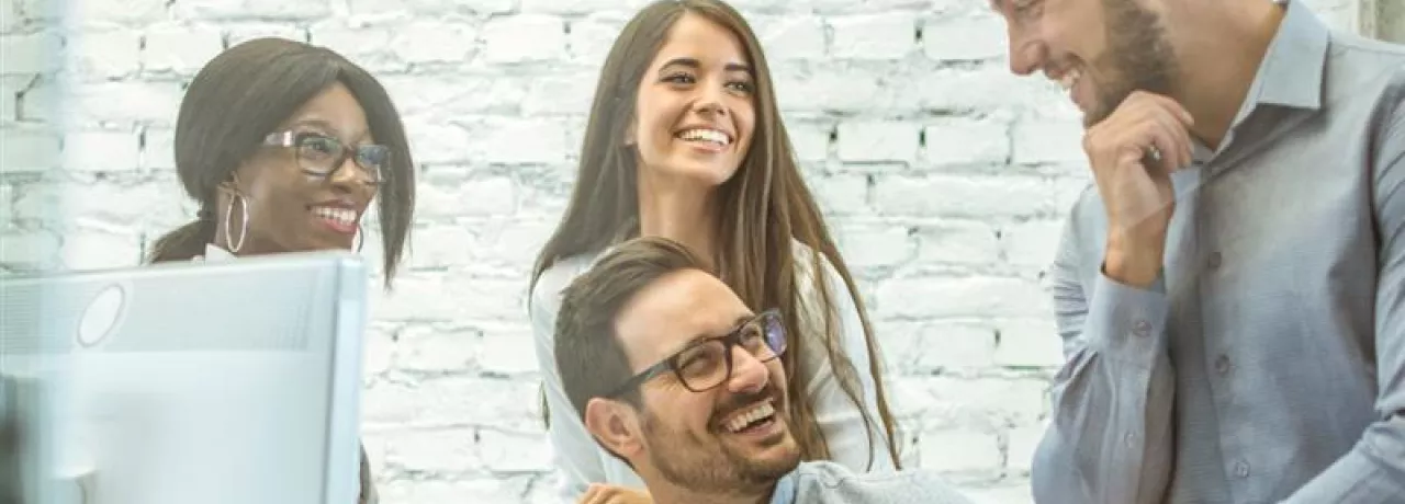 Equipo de colaboradores conversando y trabajando juntos en una oficina, representando el compromiso y la retención del personal en las empresas.