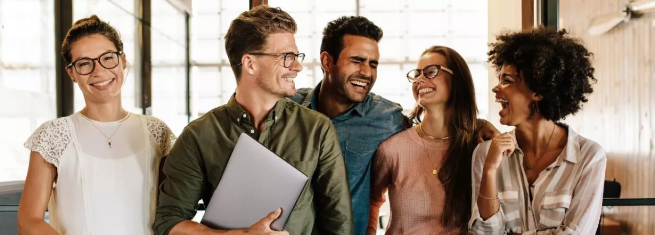 Equipo de trabajo sonriendo en la oficina, reflejando motivación y buen clima laboral en un entorno corporativo en Uruguay.