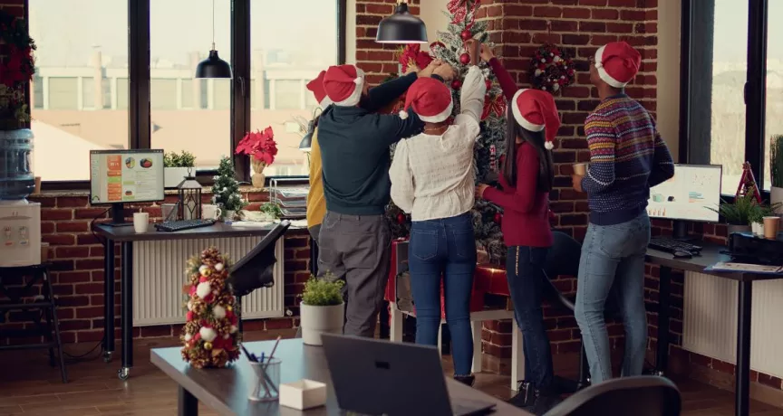 Equipo de trabajadores decorando juntos el árbol de navidad de la oficina
