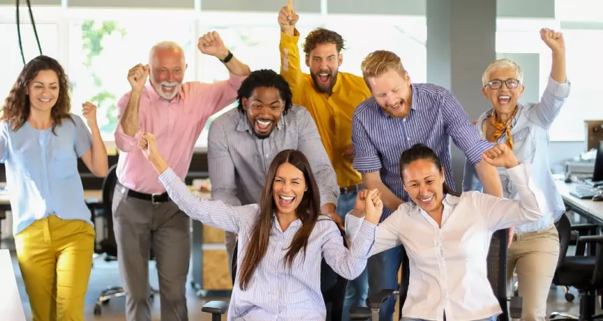 Equipo de trabajo celebrando juntos en la oficina durante una actividad de team building.