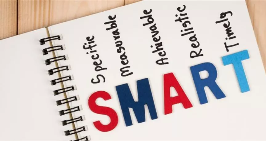 Cuaderno con la palabra SMART y sus componentes específicos, medibles, alcanzables, relevantes y con plazo, representando la metodología para definir objetivos SMART.