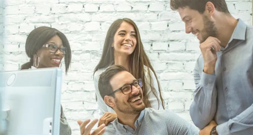 Equipo de colaboradores conversando y trabajando juntos en una oficina, representando el compromiso y la retención del personal en las empresas.