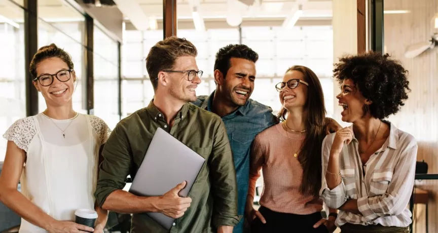 Equipo de trabajo sonriendo en la oficina, reflejando motivación y buen clima laboral en un entorno corporativo en Uruguay.