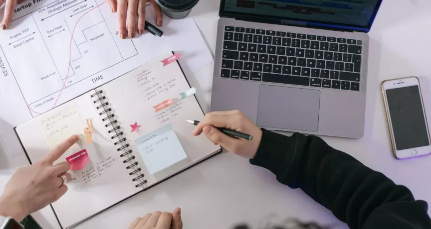 Equipo organizándose en el trabajo y gestionando tareas con agenda y computadora