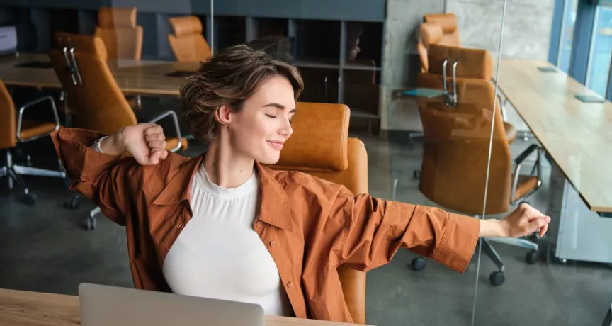 Colaboradora relajada disfrutando de sus beneficios laborales flexibles, en un entorno de trabajo moderno, enfocado en flexibilidad y bienestar