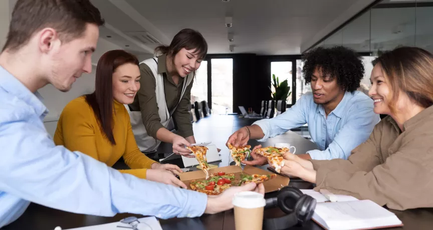 Equipo de trabajo compartiendo una comida en oficina, relacionado con gestión de gastos y reducción de costos de alimentación en una empresa