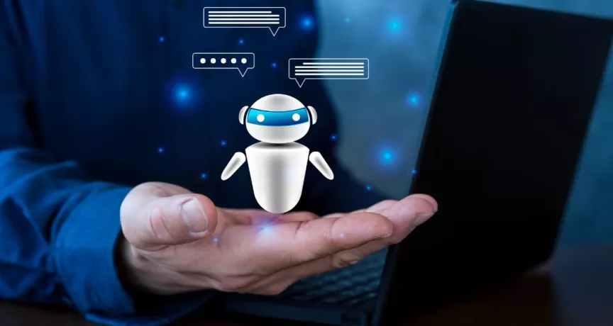 Persona sosteniendo un agente de inteligencia artificial virtual frente a una computadora, representando el uso de IA en Recursos Humanos para automatizar procesos.