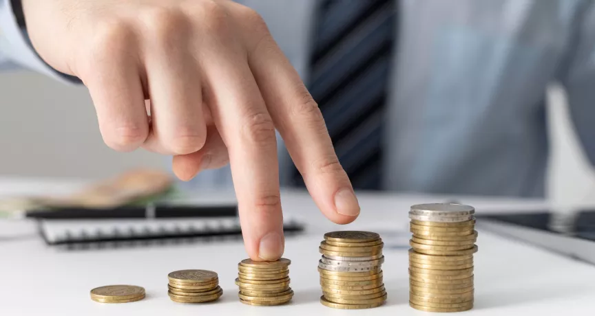 Mano acomodando pilas de monedas que representan el crecimiento de los salarios en Uruguay y la evolución del poder adquisitivo de los trabajadores.