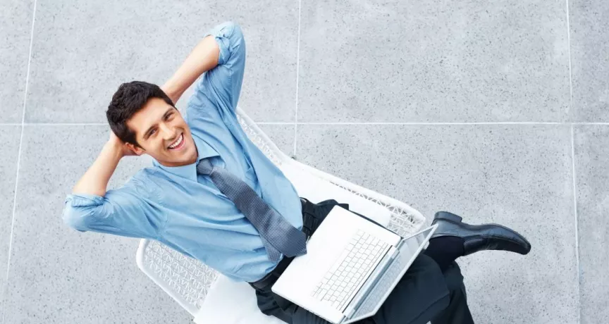 Hombre sonriente con una computadora portátil, en representación de los beneficios de la semana laboral de 4 días.