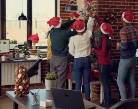 Equipo de trabajadores decorando juntos el árbol de navidad de la oficina