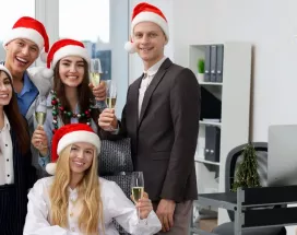 Equipo de oficina celebrando la Navidad con gorros rojos y copas de brindis
