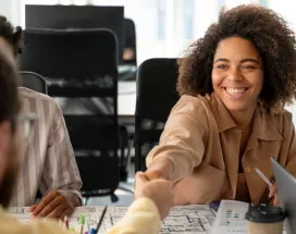 Persona joven sonriendo y estrechando la mano en una entrevista laboral, representando el crecimiento del mercado laboral uruguayo.