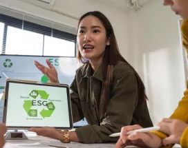 Profesional presentando una propuesta de ESG a su equipo, mostrando en una tablet los pilares de sostenibilidad ambiental, social y de gobernanza durante una reunión de trabajo.