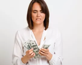 Mujer observando billetes de dinero con gesto de preocupación, reflejando la brecha entre salario real y salario percibido.