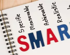 Cuaderno con la palabra SMART y sus componentes específicos, medibles, alcanzables, relevantes y con plazo, representando la metodología para definir objetivos SMART.